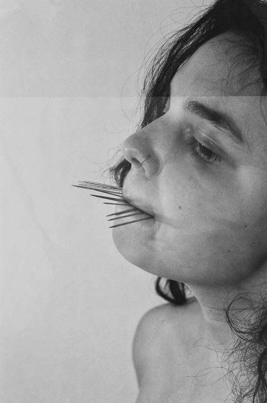 Artist Zoe Forsyth with pins in mouth to stage a photograph